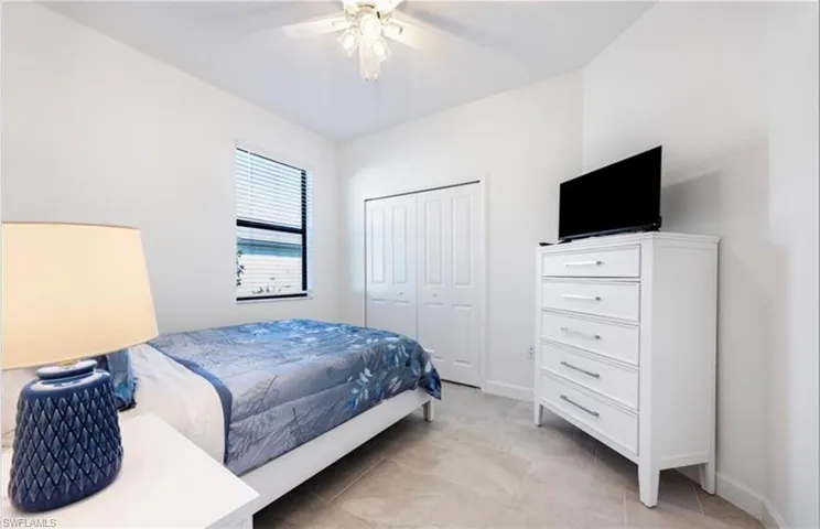 Bedroom with ceiling fan, a closet, and light tile patterned floors