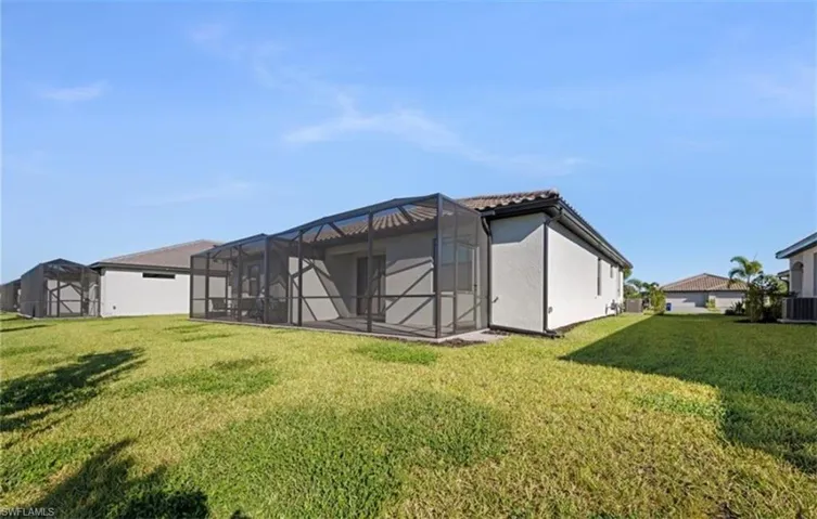 Back of house with a lanai, a yard, a sunroom, and stucco siding