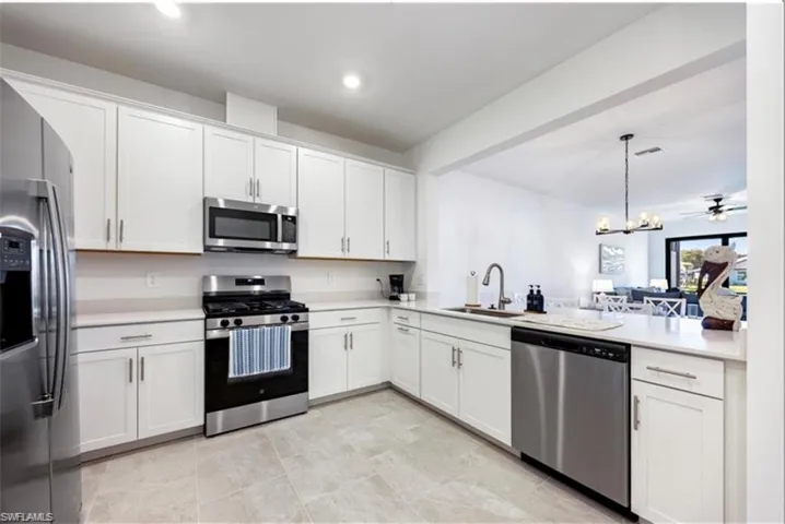 Kitchen featuring stainless steel appliances, a chandelier, white cabinetry, pendant lighting, and open floor plan