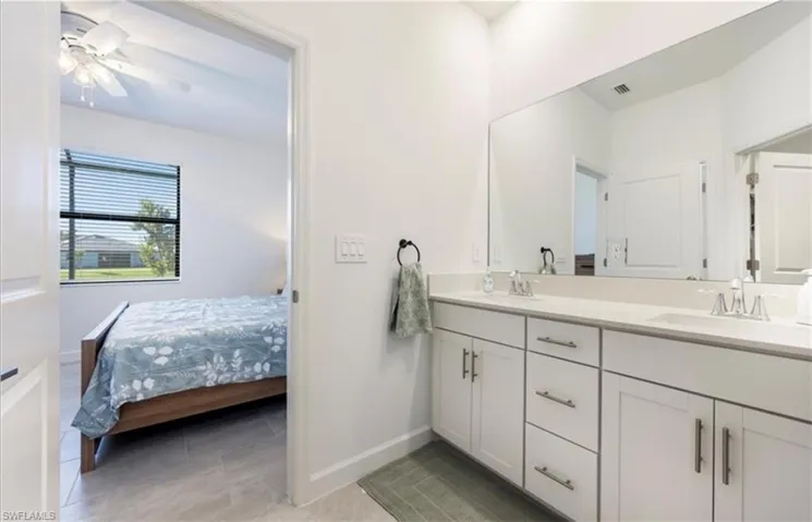 Ensuite bathroom with double vanity, ceiling fan, and light tile patterned flooring