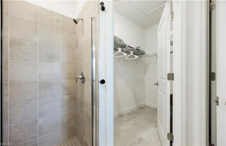 Bathroom featuring a walk in closet and a shower stall