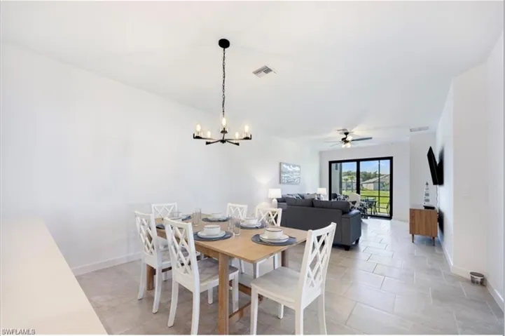 Dining room featuring ceiling fan, a chandelier, and light tile patterned flooring
