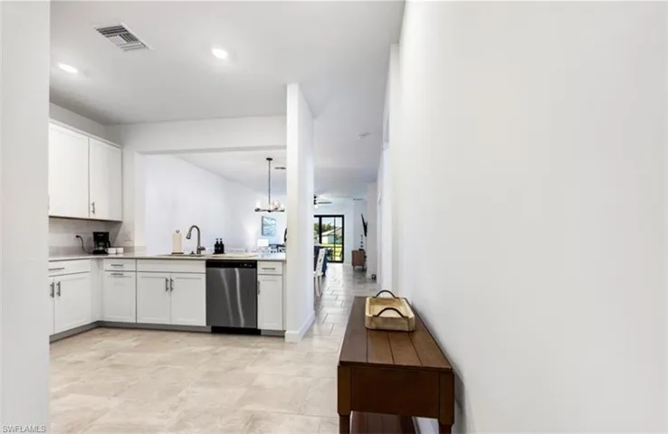 Kitchen featuring white cabinetry, dishwasher, hanging light fixtures, a chandelier, and recessed lighting