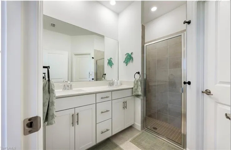 Full bathroom featuring double vanity, a shower stall, light tile patterned floors, and recessed lighting