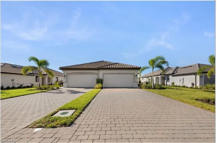 View of front of property with a front yard, decorative driveway, and stucco siding