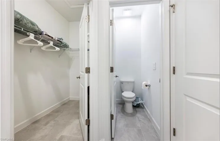Bathroom with a spacious closet and baseboards