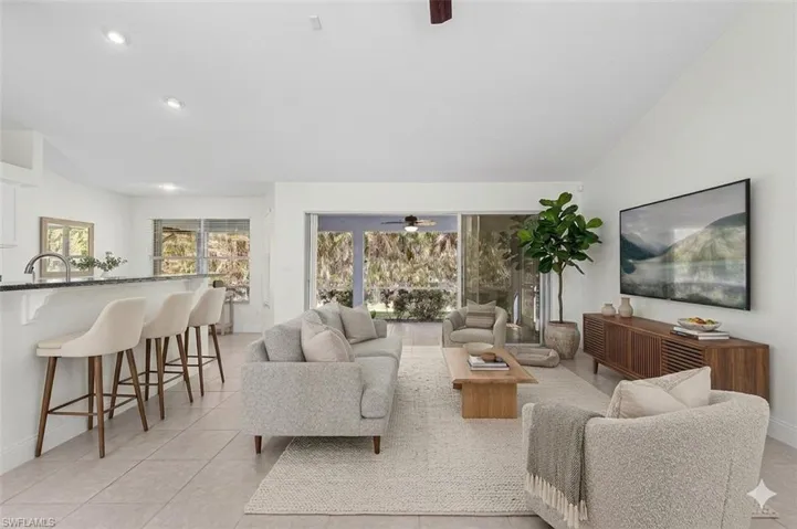 virtual staged Living area featuring ceiling fan, vaulted ceiling, and light tile patterned flooring