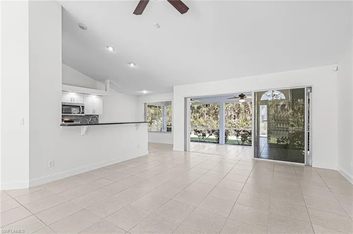 Unfurnished living room with a ceiling fan, lofted ceiling, and light tile patterned floors