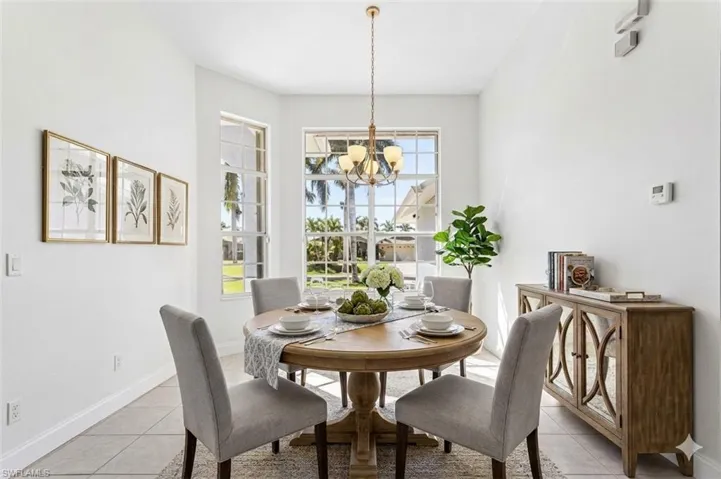 virtual staged Dining area with light tile patterned flooring and hanging lights