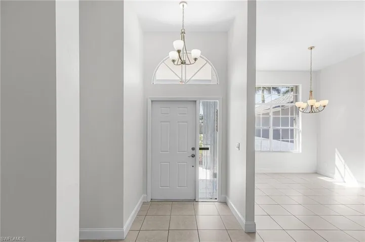 Entryway with a chandelier, plenty of natural light, light tile patterned flooring, and a high ceiling