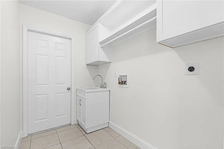 Laundry area featuring cabinet space, light tile patterned floors, washer hookup, and electric dryer hookup