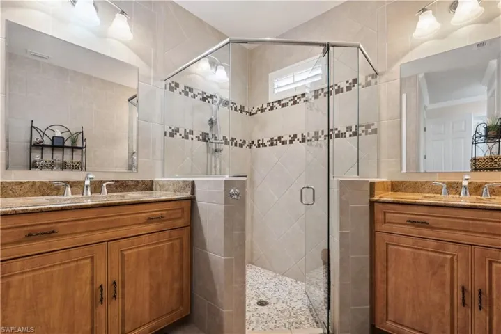 Bathroom with vanity, a shower with shower door, and tile walls