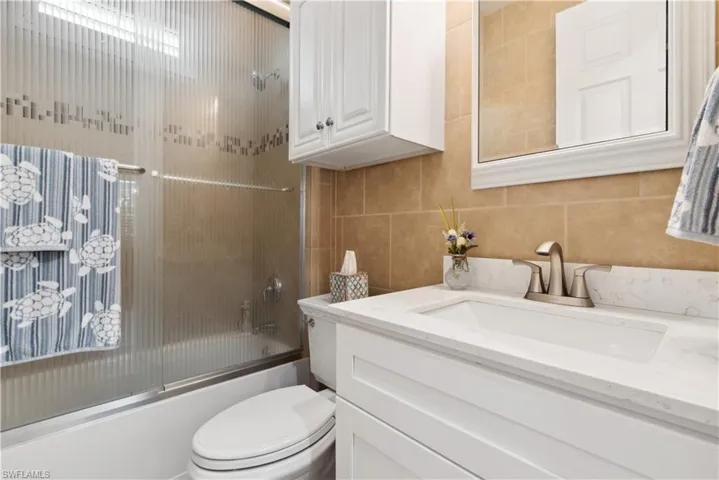 Full bathroom featuring vanity, toilet, and bath / shower combo with glass door