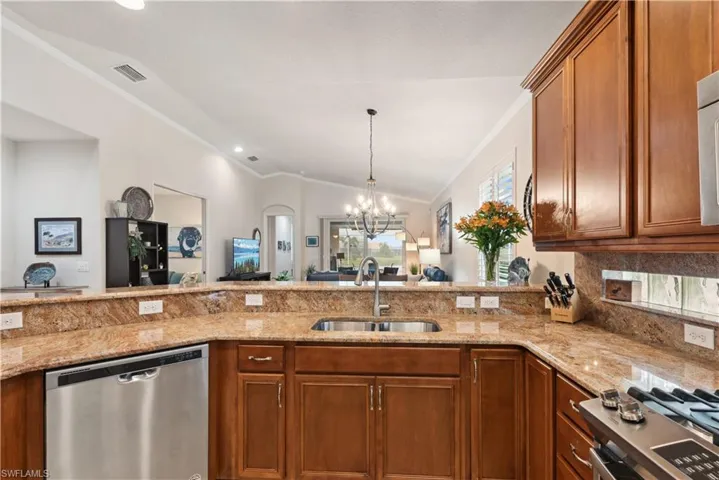 Kitchen with stainless steel dishwasher, vaulted ceiling, sink, an inviting chandelier, and range