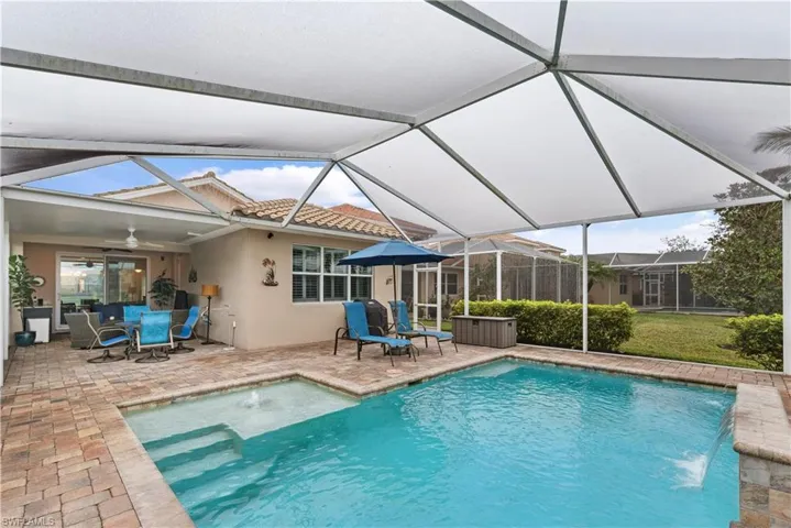 View of swimming pool featuring glass enclosure, pool water feature, ceiling fan, and a patio