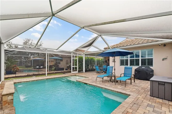 View of swimming pool with a lanai, grilling area, pool water feature, and a patio area