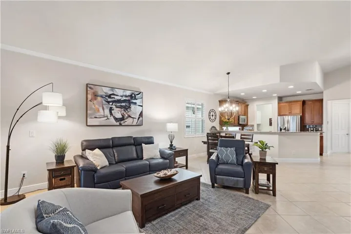 Tiled living room featuring ornamental molding and a chandelier