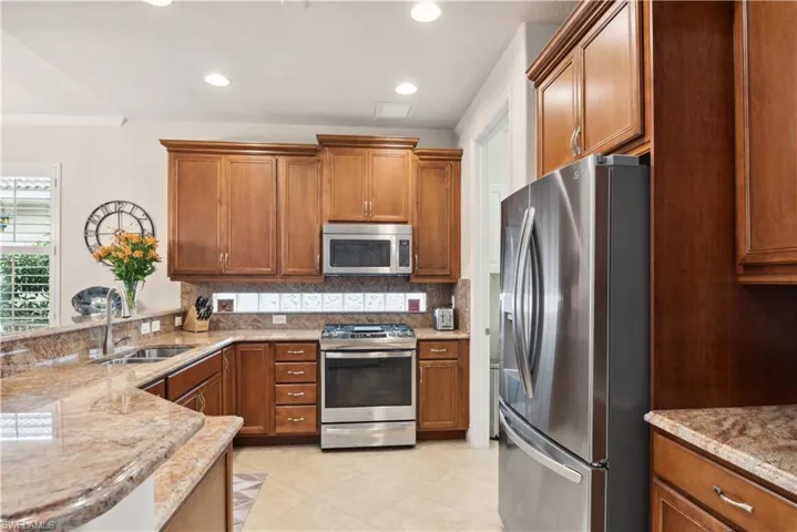 Kitchen featuring sink, light stone countertops, light tile patterned floors, tasteful backsplash, and stainless steel appliances