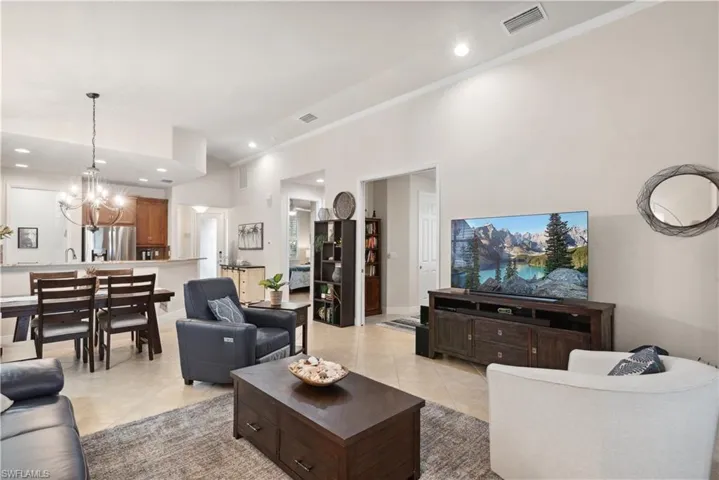 Living room with light tile patterned flooring, ornamental molding, and an inviting chandelier