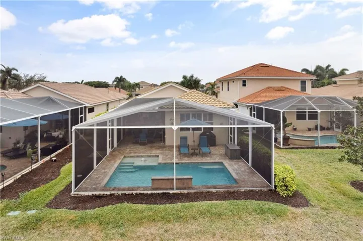 Rear view of property with a lawn, glass enclosure, and a patio