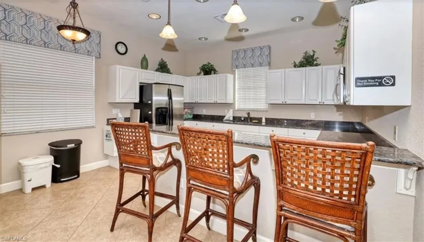 Kitchen with a breakfast bar area, a peninsula, white cabinets, stainless steel appliances, and dark stone countertops