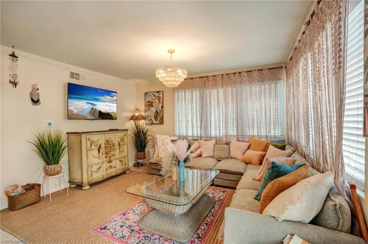Living area featuring a chandelier and crown molding- Virtually Edited Image