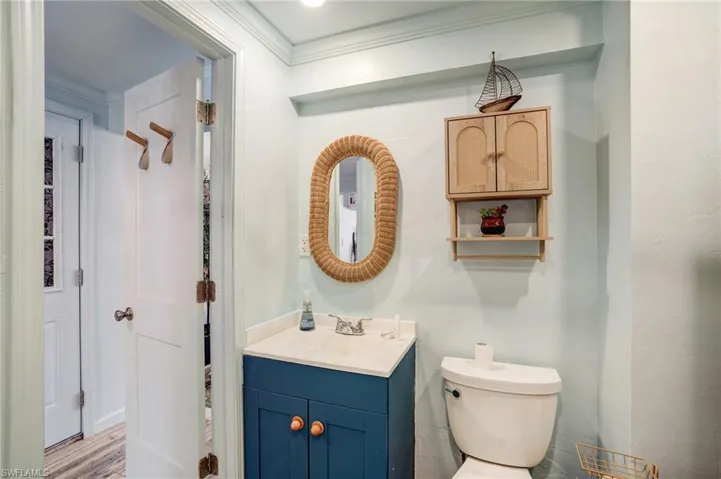 Bathroom featuring vanity, toilet, and crown molding- Virtually Edited Image