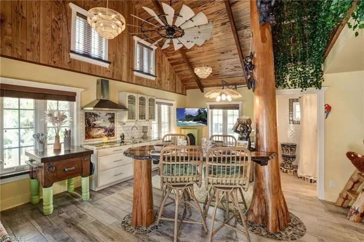 Dining area featuring light wood-style flooring, plenty of natural light, wooden ceiling, ceiling fan, and high vaulted ceiling - Virtually Edited Image