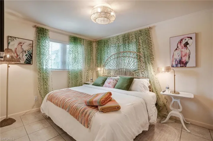 Bedroom featuring tile patterned flooring, ornamental molding, and baseboards- Virtually Edited Image