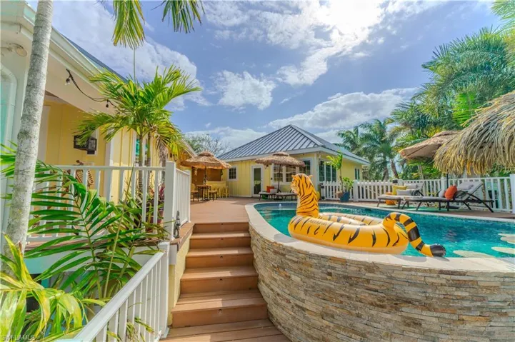 View of swimming pool featuring a wooden deck and stairway- Virtually Edited Image