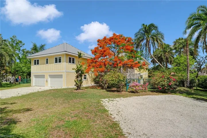 View of back of house featuring a front lawn, driveway, and an attached garage - Virtually Edited Image