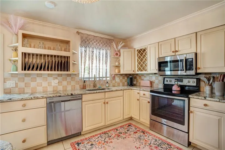 Kitchen with open shelves, stainless steel appliances, a sink, cream cabinetry, and backsplash- Virtually Edited Image