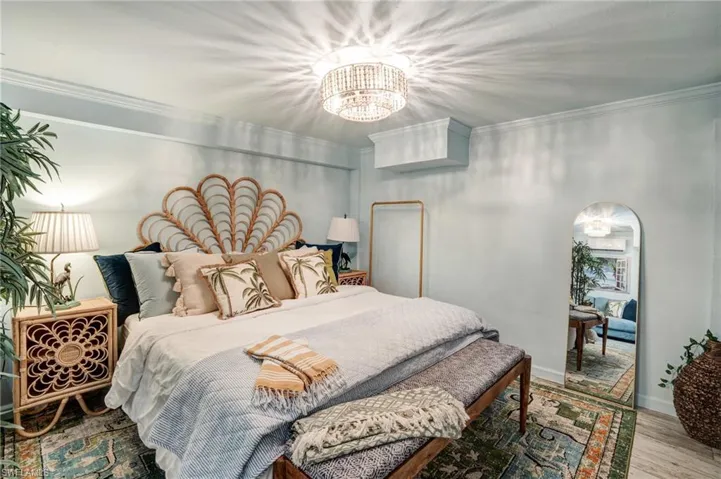 Bedroom featuring a chandelier, ornamental molding, and wood finished floors- Virtually Edited Image