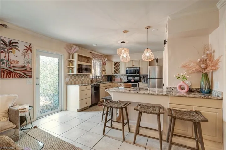 Kitchen featuring appliances with stainless steel finishes, a peninsula, crown molding, open shelves, and backsplash- Virtually Edited Image