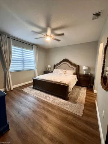 Spacious room featuring wood-finish flooring, a ceiling fan with integrated lighting, and neutral wall tones