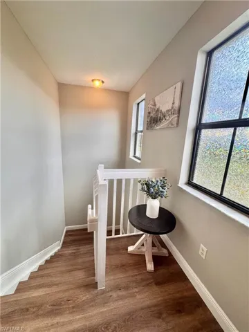 Staircase featuring wood-finish flooring, white balusters, and a white handrail