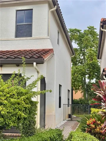 Stucco exterior with terracotta-style roof tiles and white gutters