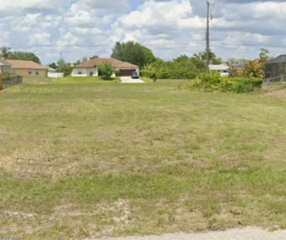 Expansive lot featuring a grass lawn and surrounding residential properties