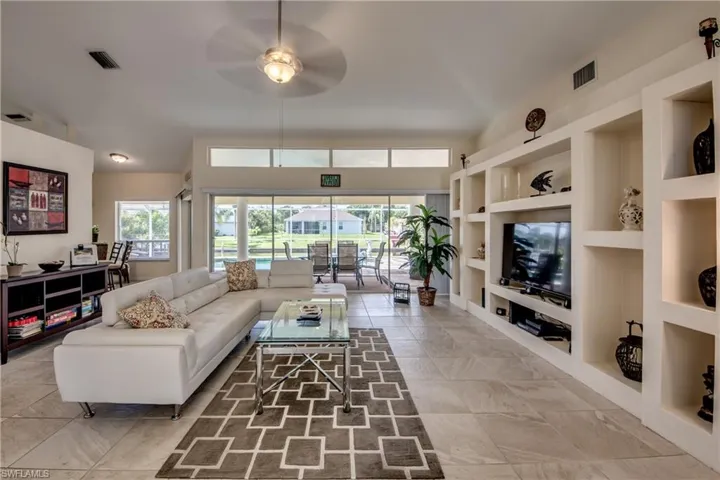 Living area featuring built in features, plenty of natural light, and a ceiling fan