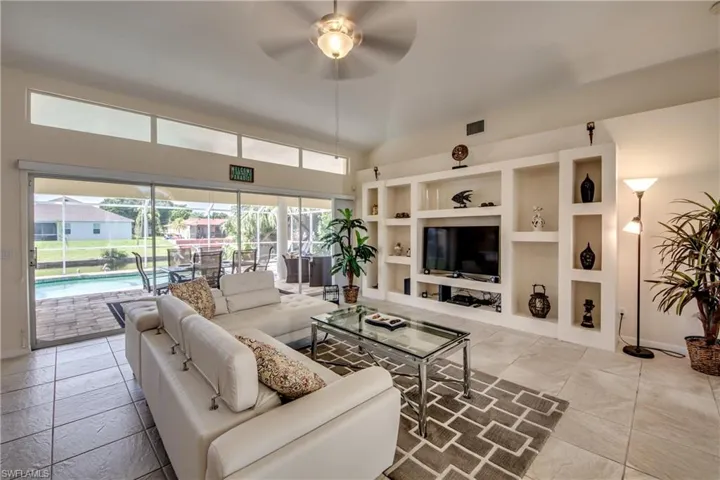 Living room with a ceiling fan, a sunroom, and built in features