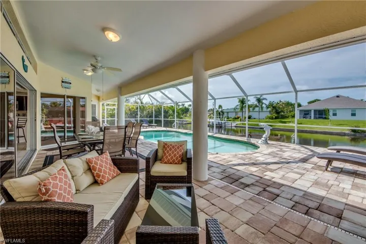 View of patio with an outdoor pool, a sunroom, a water view, and a ceiling fan