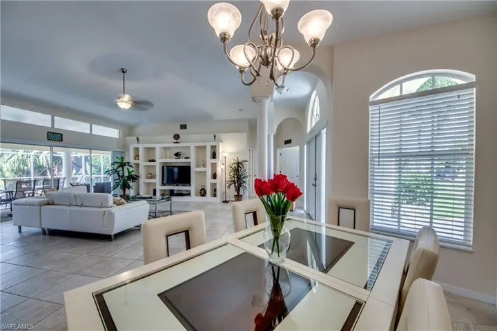 Dining room with a ceiling fan, light tile patterned flooring, and arched walkways
