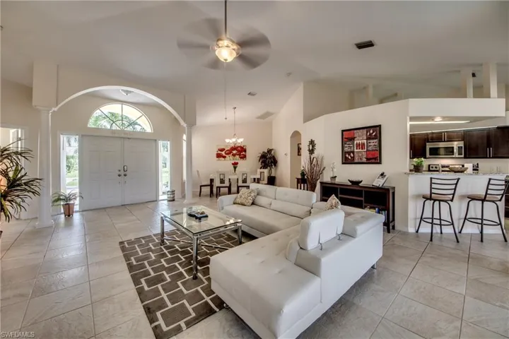 Living room with high vaulted ceiling, a chandelier, ceiling fan, and arched walkways