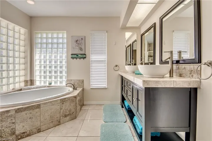 Bathroom with vanity, a garden tub, and light tile patterned floors