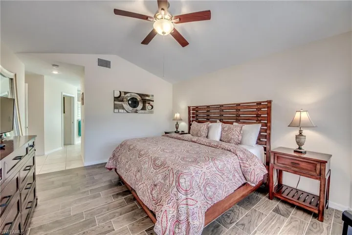 Bedroom featuring vaulted ceiling, wood tiled floors, and ceiling fan