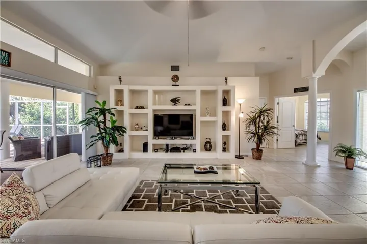 Living room with plenty of natural light, arched walkways, light tile patterned floors, and decorative columns
