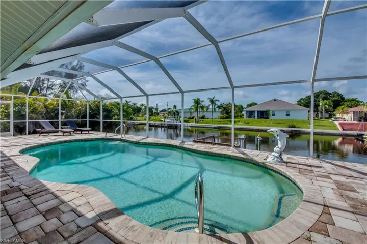 Swimming pool with a lanai, a sunroom, a water view, a patio area, and a boat dock