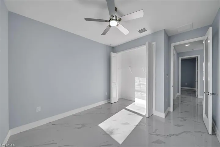 Unfurnished bedroom featuring a closet, baseboards, visible vents, ceiling fan, and marble finish floor