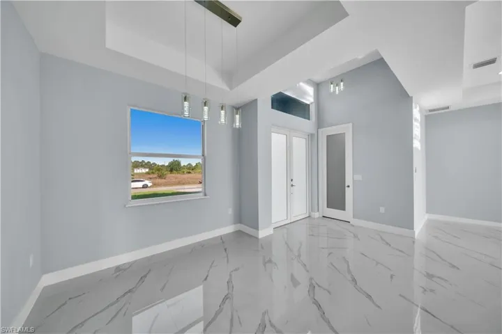 Unfurnished room with a tray ceiling, visible vents, baseboards, and marble finish floor