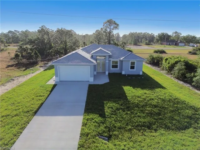 View of front of home with a front yard, an attached garage, stucco siding, and concrete driveway